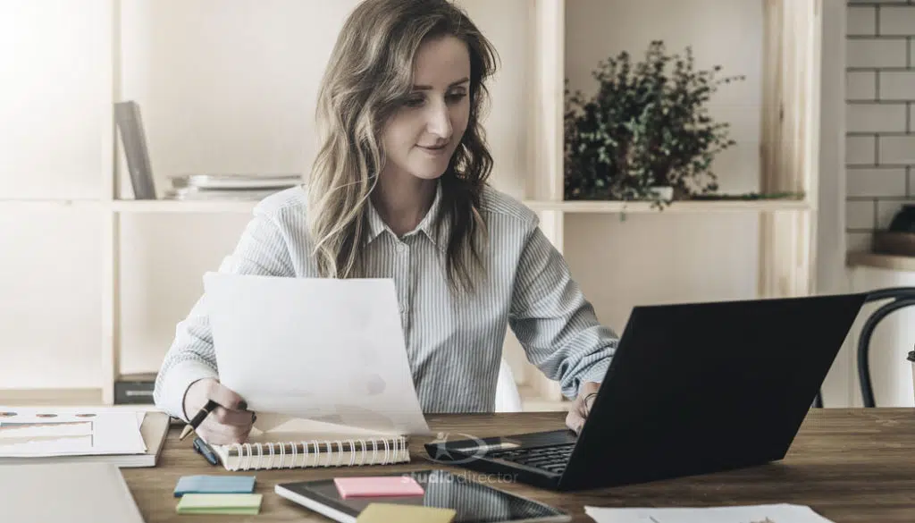 a person working on a computer while holding a piece of paper